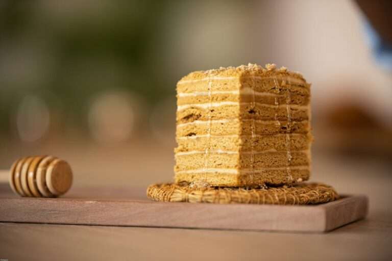 Delicious slice of layered Medovik honey cake on a rustic wooden board with honey drizzle.