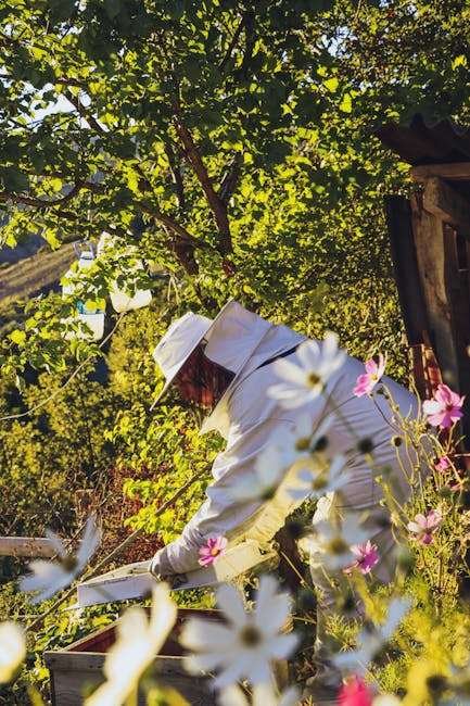 Beekeeper in a protective suit tending to beehives amidst vibrant spring flowers.