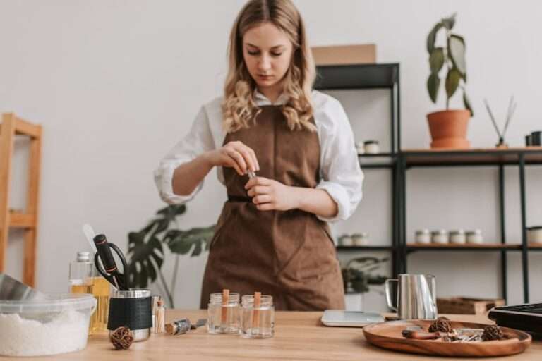 Woman in apron making candles on a wooden counter with various ingredients and tools.